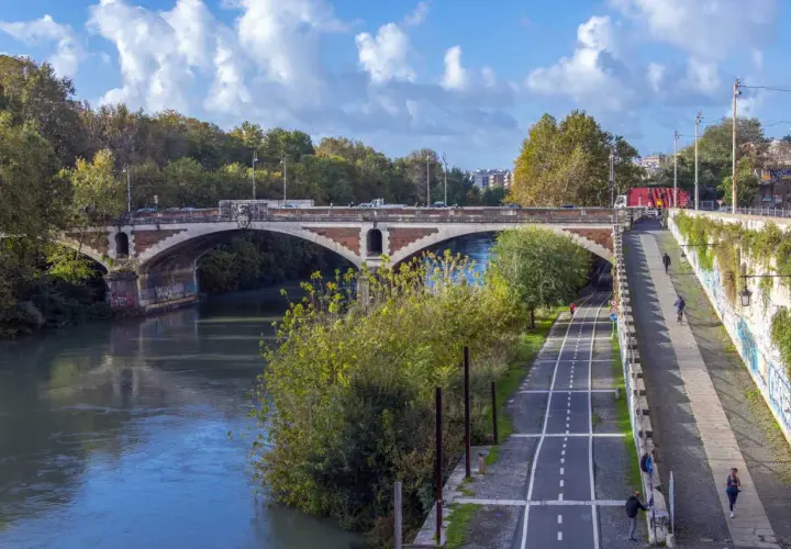 Il ponte nuovo di Roma attraversa il Tevere, con una pista ciclabile e pedonale lungo la riva.