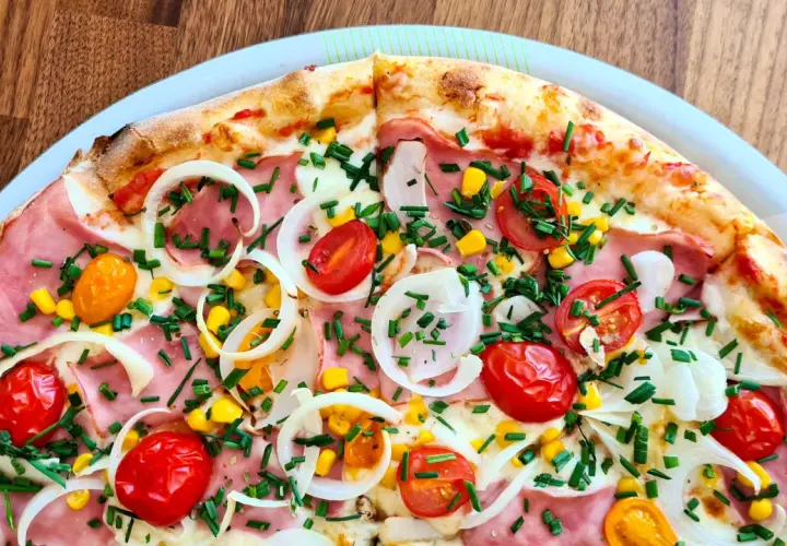 Pyszna pizza 32 cm na ile osób? Ta z szynką, pomidorkami, kukurydzą i cebulą z pewnością zadowoli 2-3 głodomorów.