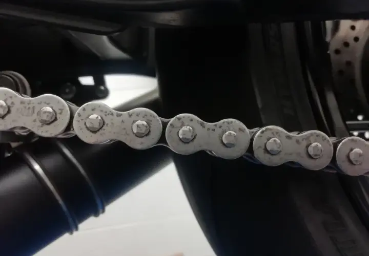 La catena di una moto mostra segni di ruggine, indicando la necessità di manutenzione.