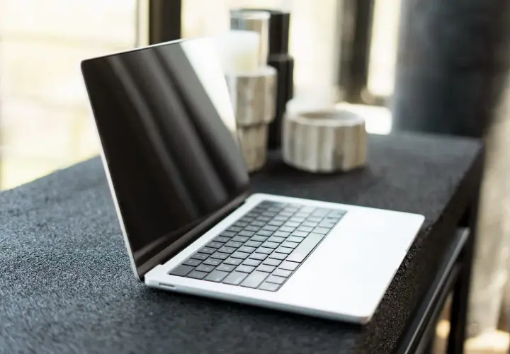Otwarty MacBook na czarnym blacie. Dowiedz się, jak zmienić język w MacBook, aby dostosować go do swoich potrzeb.