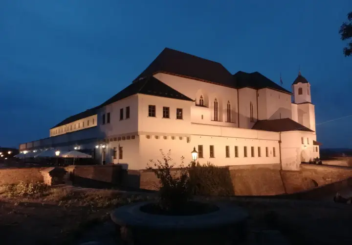 Brno zamek nocą, oświetlony, z wieżą i murami obronnymi.