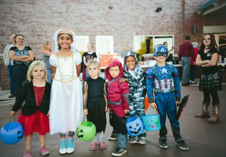 Dzieci w strojach na Halloween, gotowe na psikusy i zbieranie słodyczy. Wśród nich księżniczka, Kapitan Ameryka i inne postacie.