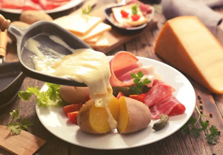 Raclette, le meilleur plat français, avec pommes de terre, charcuterie et fromage fondu. Un délice réconfortant.