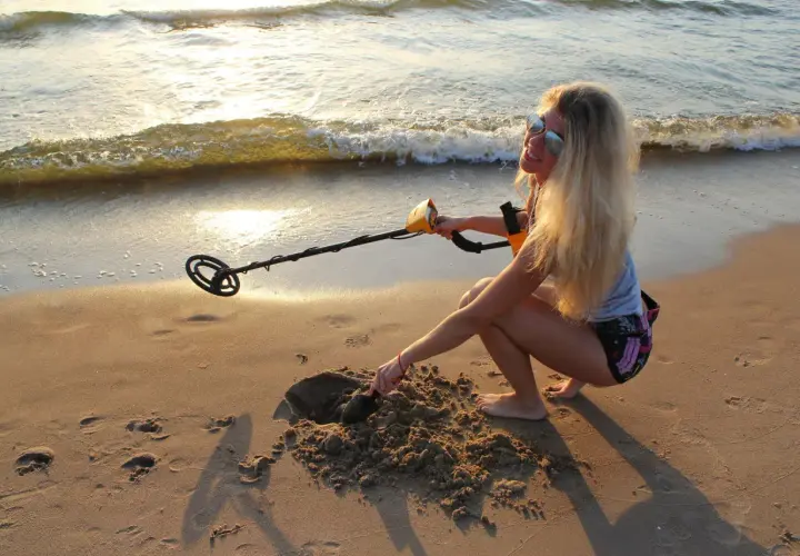 Dziewczyna z wykrywaczem metali na plaży. Czy można chodzić z wykrywaczem po plaży? Ona właśnie kopie w piasku, szukając skarbów.