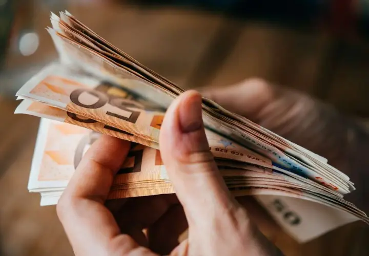 Hände halten einen Stapel Euro-Scheine. Dies könnte relevant sein für den **privatinsolvenz freibetrag**.