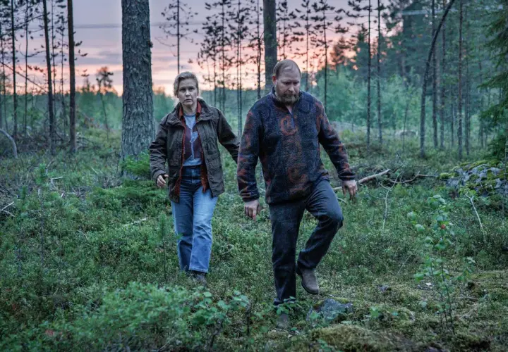 Två personer går genom en skog i skymningen. Det är en scen från Vargasommar del 2.