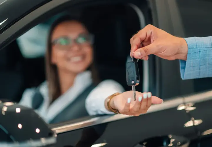 Kluczyki do nowego auta przekazuje uśmiechnięta kobieta, która skorzystała z oferty mbank leasing.
