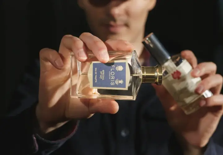 Mężczyzna trzyma perfumy Floris Special No 127. W składzie może być benzoesan benzylu, nadający zapachowi głębi.