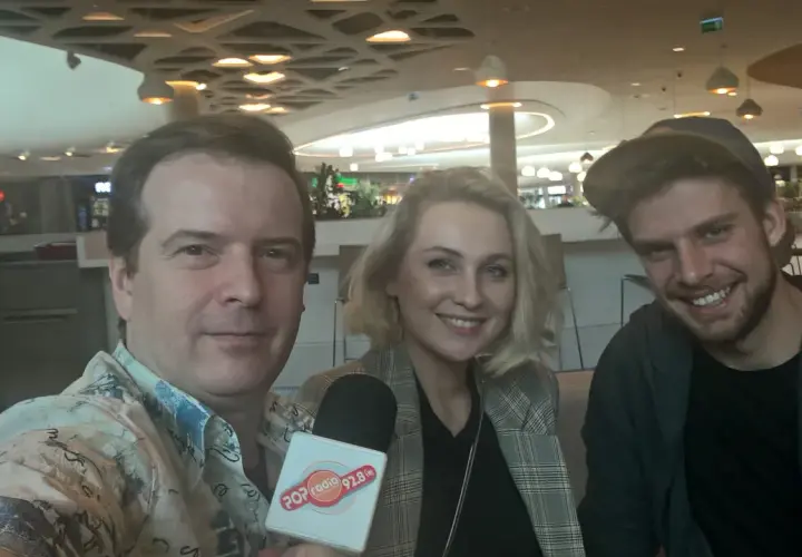Trzy osoby pozujące do zdjęcia z mikrofonem Popradio.