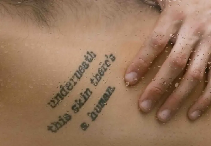 Mądre cytaty na tatuaż po angielsku: "Underneath this skin there's a human". Dłoń na mokrej skórze.