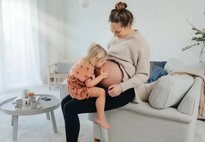 Liten flicka kramar sin mammas mage. En fin stund för blivande storasyster, som snart får en lillebror eller lillasyster. Folsyra är viktigt för en frisk graviditet.