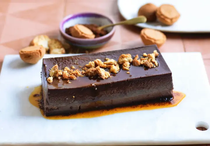 Bonet piemontese al cioccolato, lucido e cremoso, guarnito con briciole croccanti e salsa caramello.