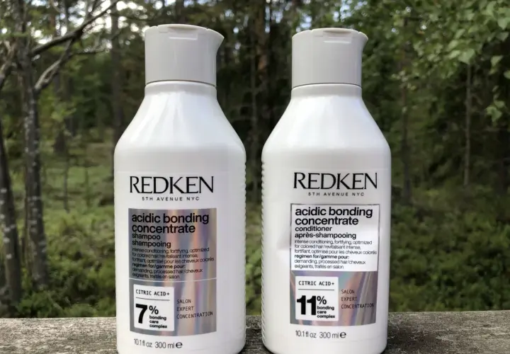 Två flaskor Redken Acidic Bonding Concentrate, schampo och balsam, står utomhus. Perfekt för att reparera skadat hår efter färgning.