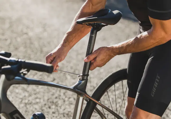 Rowerzysta reguluje wysokość siodełka, by uzyskać optymalną pozycję na rowerze szosowym.