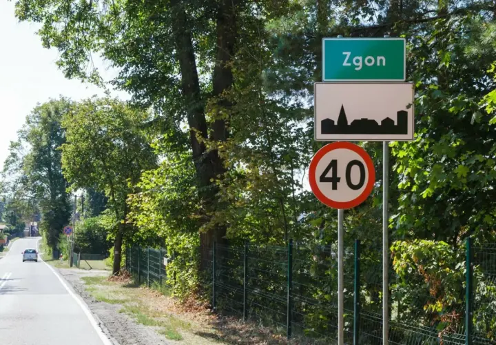 Zielony znak miejscowości Zgoń, obok znak z sylwetką miasta i ograniczenie prędkości do 40 km/h.