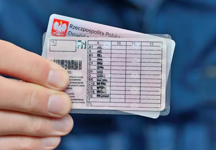 Dłoń trzyma polskie prawo jazdy. Zastanawiasz się, ile kosztuje prawo jazdy kat B? Dokument zawiera kategorie pojazdów.