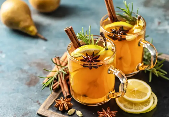 Due bicchieri di hot toddy ricetta con cannella, anice stellato, limone e pera. Perfetto per scaldarsi.