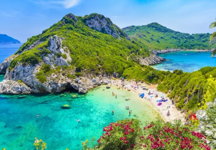 Malownicza zatoka z turkusową wodą i piaszczystą plażą. W maju Grecja zachwyca zielenią i kwitnącymi kwiatami.