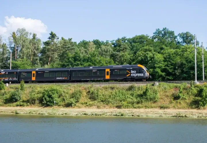 Czarny pociąg Leo Express jedzie wzdłuż zielonego brzegu. Zastanawiasz się, ile kosztuje bilet z Warszawy do Krakowa?