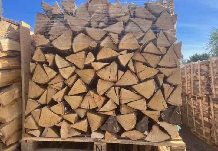 Un grand stère de bois, bien empilé et emballé sous plastique, prêt pour l'hiver.