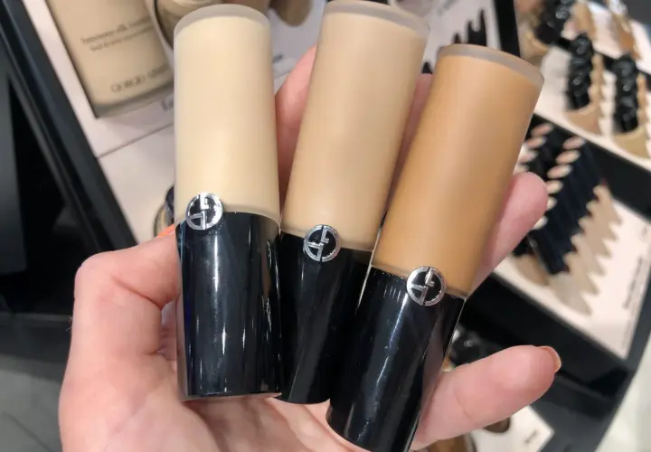 En hand håller tre flaskor Giorgio Armani foundation i olika nyanser.