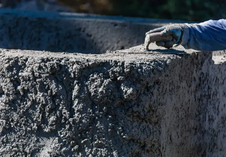 Ręka w rękawicy wygładza świeży beton. Zastanawiasz się, ile kosztuje worek cementu do takiej pracy?