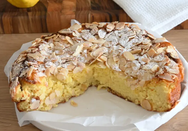 Delizioso dolce senza glutine con mandorle a lamelle e zucchero a velo, su un piatto bianco.
