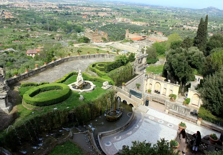Vue panoramique de la Villa d'Este, avec ses jardins en terrasse, ses fontaines et sa statue, dominant la campagne environnante.