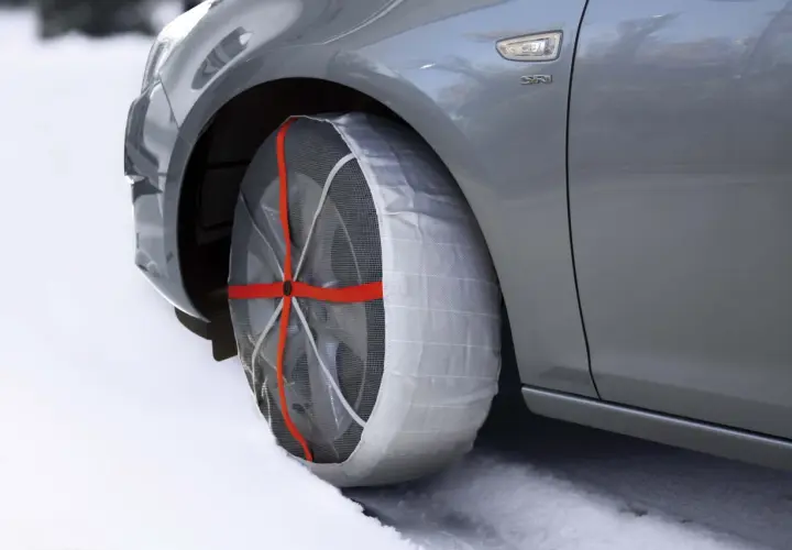 Neumático de coche con cadenas de nieve puestas, ideal para saber donde se colocan las cadenas de nieve en condiciones de hielo.