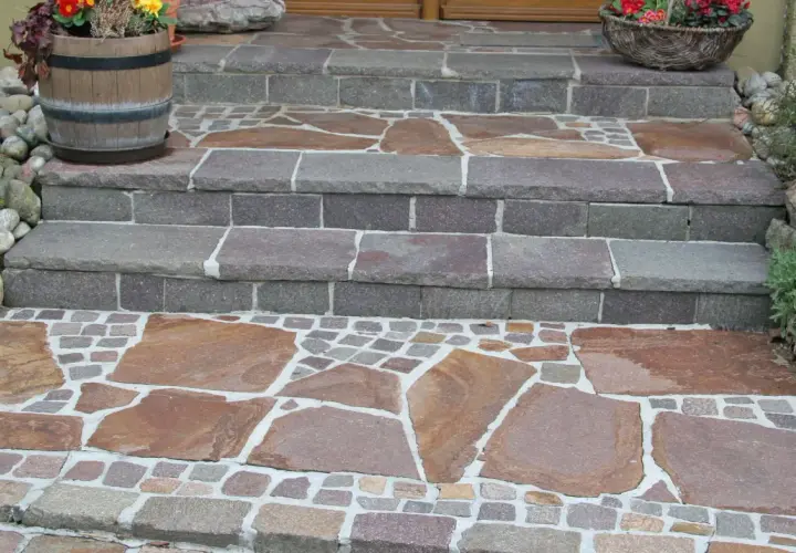 Stufen mit polygonalplatten verlegen. Große, unregelmäßige Steinplatten wechseln sich mit kleinen, quadratischen Pflastersteinen ab.