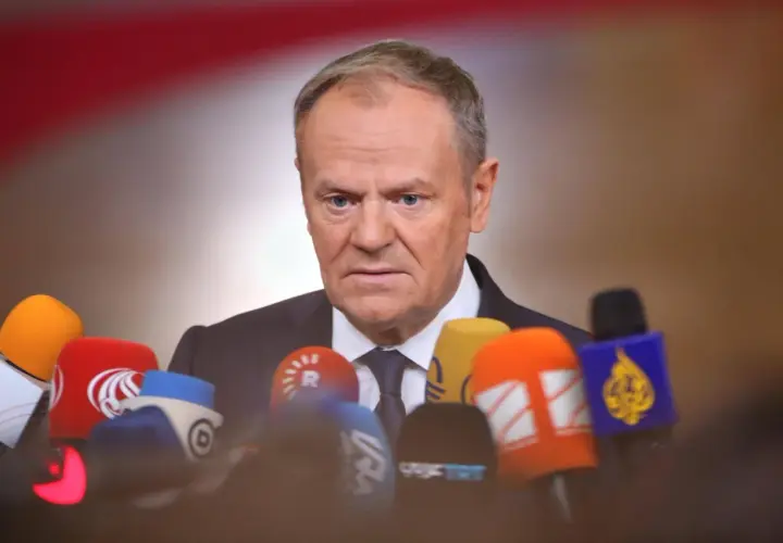 Donald Tusk w Ustroniu, otoczony przez mikrofony mediów, gotów do udzielenia wywiadu.