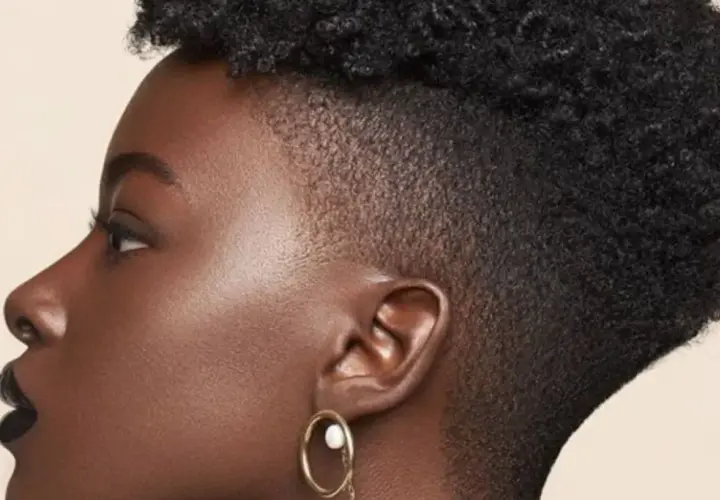 Perfil de mujer con cabello rizado y un moderno taper fade bajo.