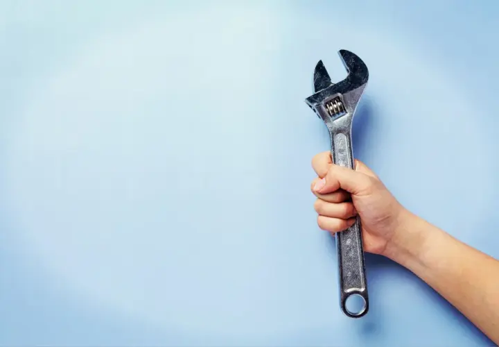 Mano sujetando una llave inglesa ajustable, útil para saber el par de apriete de un tornillo.