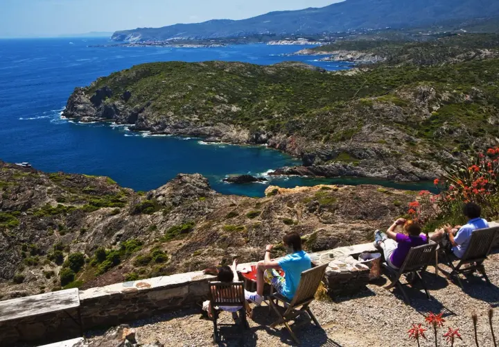 Disfrutando de la vista del Cap de Creus, con sus calas y montañas, mientras la gente descansa en sillas.