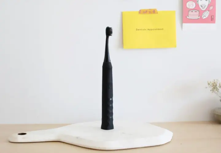 Czarna szczoteczka soniczna na białej desce, obok żółtej kartki z napisem "Dentists Appointment".