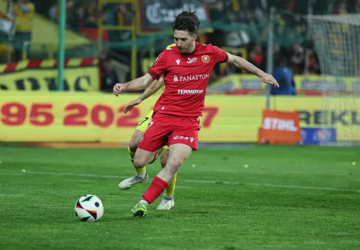 GKS Katowice piłkarze w akcji. Zawodnik w czerwonej koszulce drybluje z piłką na boisku, walcząc o zwycięstwo.