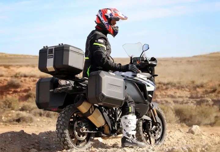 Motociclista con casco y equipo de aventura, listo para explorar. Como se llama el maletero de la moto, es un accesorio esencial para llevar todo lo necesario.