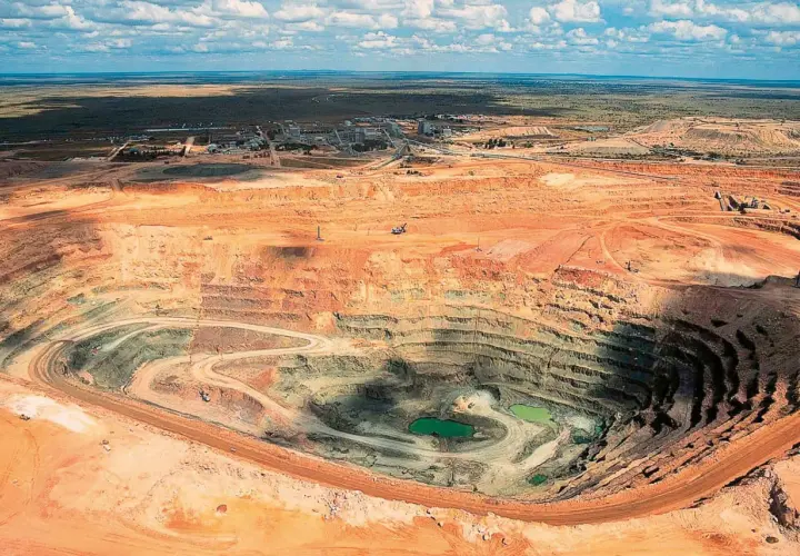 Tiefer Krater einer Mine, wo der **diamanten abbau** stattfindet. Grüne Wasseransammlungen am Grund.