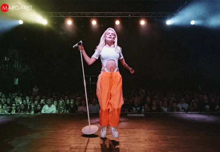 Margaret, dziękuję bardzo za wspaniały koncert! Wokalistka na scenie z mikrofonem, w pomarańczowych spodniach, przed rozentuzjazmowaną publicznością.