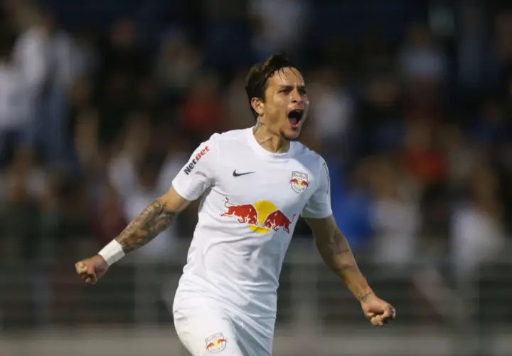 Piłkarz w białej koszulce z logo Red Bull świętuje bramkę. Wśród najlepszych brazylijskich piłkarzy, jego radość jest zaraźliwa.