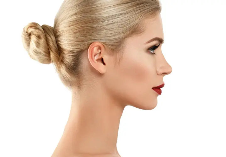 Profil kobiety z blond kokiem i subtelnym garbatym nosem, podkreślonym czerwonymi ustami.