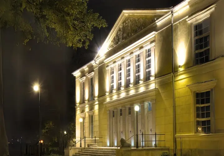 Elegancki budynek teatru w Jeleniej Górze nocą, oświetlony ciepłym światłem.