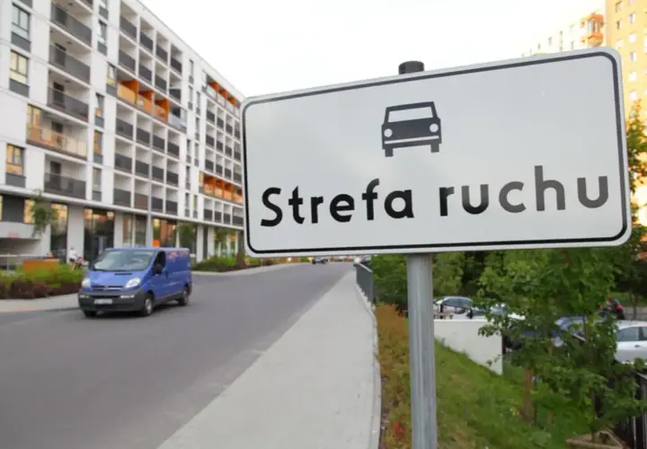Znak "Strefa ruchu" na drodze wewnętrznej obok nowoczesnego osiedla.