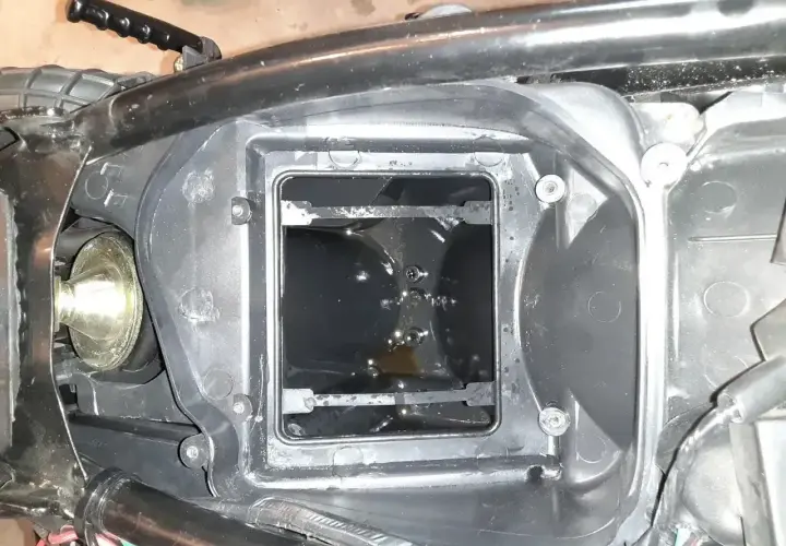 W komorze filtra powietrza motocykla widać ciemny olej w odmie.