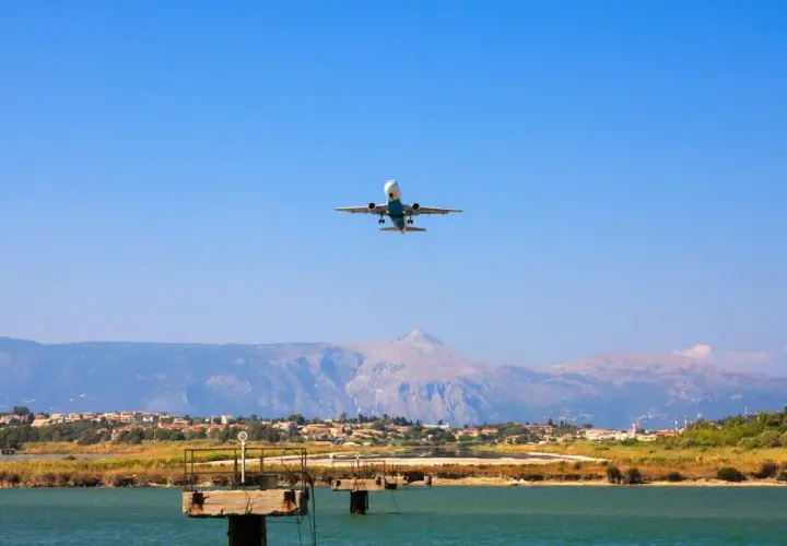 Airplane ascending over a coastal town near the Sicily airport, with mountains in the background.