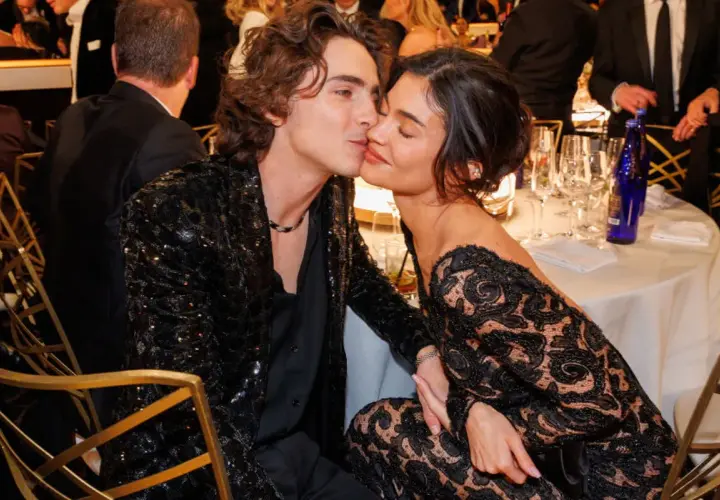 Kylie Jenner i Timothée Chalamet w czarnych, eleganckich strojach, podczas romantycznego momentu przy stole.