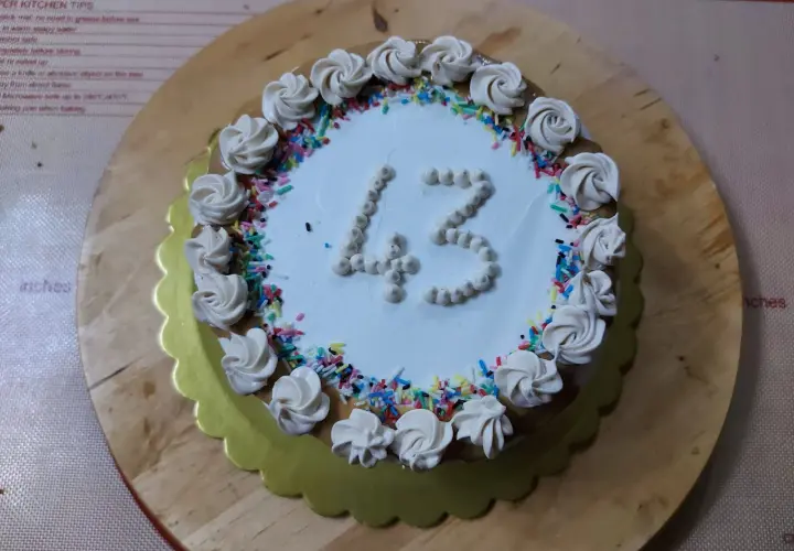 Torta di compleanno particolare con decorazioni a rosa e codette colorate, numero 43 in crema.