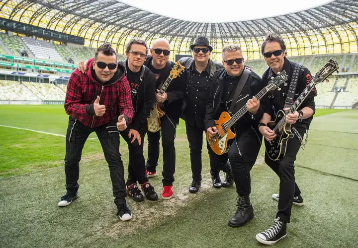 Zespół Big Cyc na murawie stadionu, gotowy do zagrania swoich największych hitów.