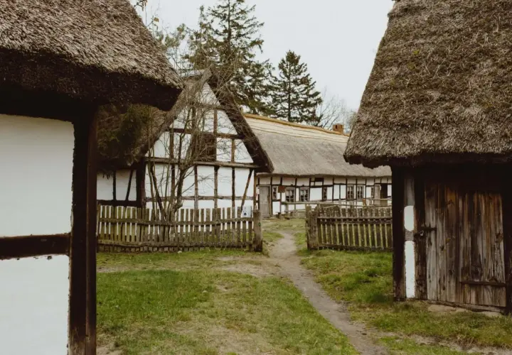 Skansen z chatami krytymi strzechą, drewnianymi płotkami i ścieżką. Idealne miejsce na odkrywanie kluki atrakcje.