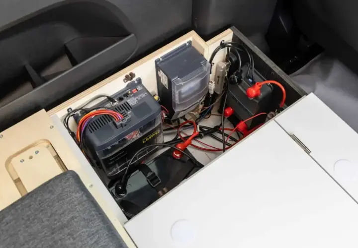 Système de batteries et de câblage pour un chauffage pour van sans électricité. L'installation est bien rangée dans un compartiment en bois.